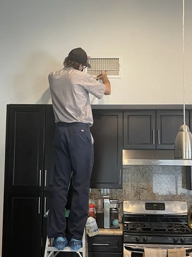 Technician inspecting an air vent during HVAC service in Hidalgo